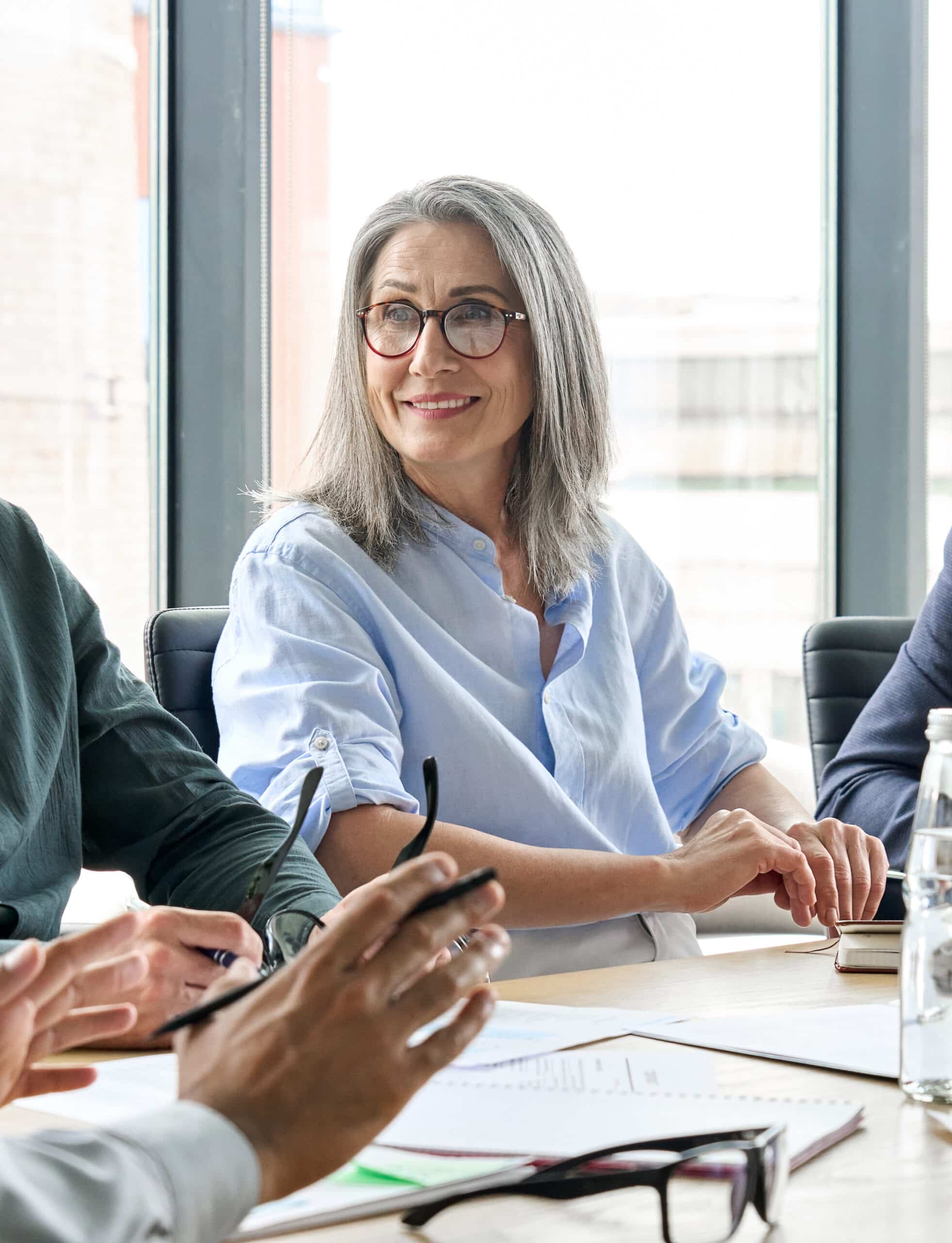 Smiling female ceo looking at male manager colleague at table meeting.